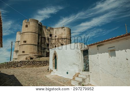 Humble House With Old Plaster Wall On Sunny Day And Castle In The Background At Evoramonte. A Tiny F