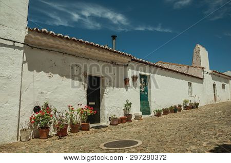 Humble White Wall Houses With Flowers Pots In A Sunny Day, On The Cobblestone Main Street Of Evoramo