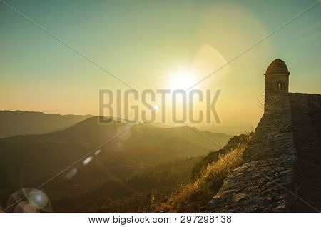 Small Watchtower And Stone Wall Over Rocky Cliff, With Hilly Landscape And Sunset Glow At Marvao. An
