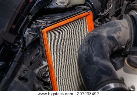 Close-up On A Dirty Air Filter For An Engine With An Orange Frame Installed In The Engine Compartmen