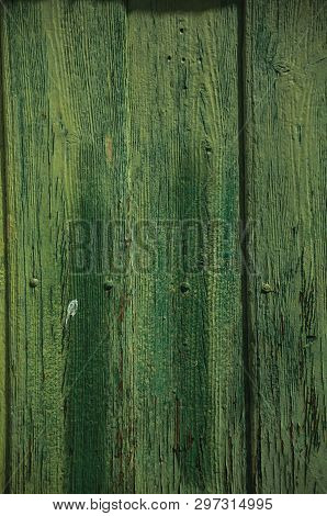 Close-up of worn planks with peeling paint in an old green door, forming a singular background near Monsanto. Considered one of the cutest and most peculiar historic village of Portugal.