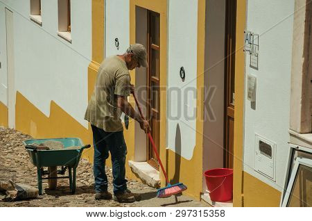 Man Sweeping The Front Of House In Street Of Evoramonte