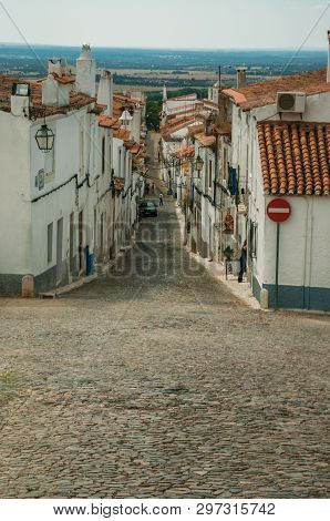 Estremoz, Portugal - July 06, 2018. Alley of old houses on slope and cobblestone causeway in a cloudy day at Estremoz. A nice little historic town with several marble buildings on eastern Portugal.