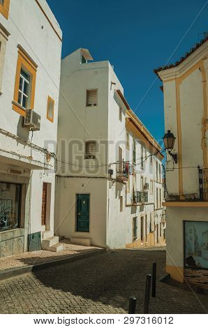 Elvas, Portugal - July 07, 2018. Alley with old colorful house facade and deserted causeway on sunny day at Elvas. A gracious star-shaped fortress city on the easternmost frontier of Portugal.