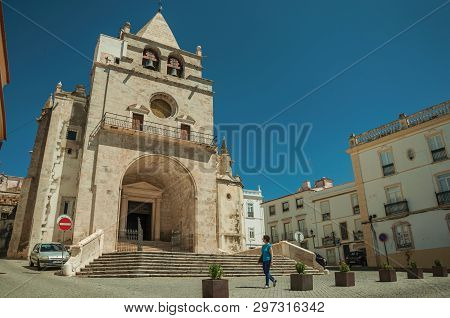Elvas, Portugal - July 7, 2018. Our Lady of the Assumption Cathedral and woman walking on a square, in a sunny day at Elvas. A star-shaped fortress city on the easternmost frontier of Portugal.