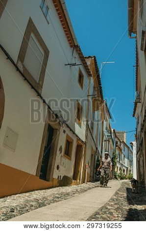 Castelo De Vide, Portugal - July 10, 2018. Elder And Dog Walking Down Narrow Alley With Old Houses A