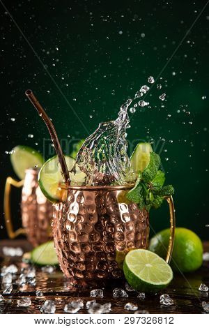 Famous splashing Moscow mule alcoholic cocktail in copper mugs, freeze motion effect.