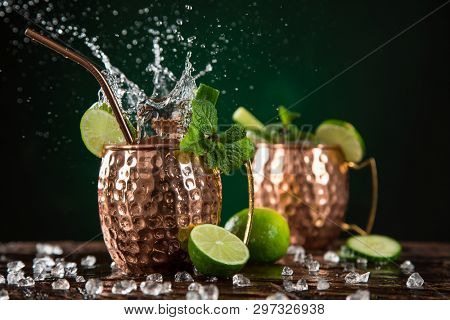 Famous splashing Moscow mule alcoholic cocktail in copper mugs, freeze motion effect.