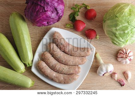 Raw Meat Sausages Kupaty And Vegetables - Cabbage, Zucchini, Radish And Garlic On Wooden Background