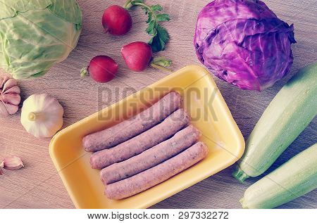 Raw Meat Sausages Kupaty And Vegetables - Cabbage, Zucchini, Radish And Garlic On Wooden Background 