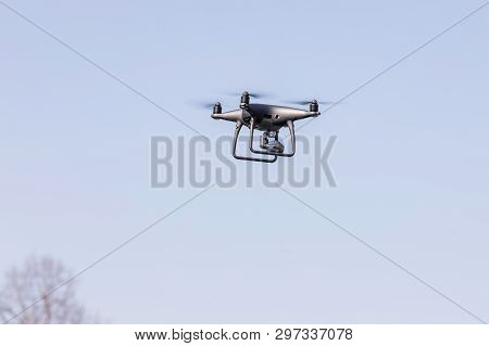 Flying Drone On The Blue Sky. Modern Silver Drone Flying.