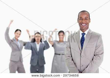 Close-up of a happy businessman smiling with enthusiastic co-workers raising their arms in the background
