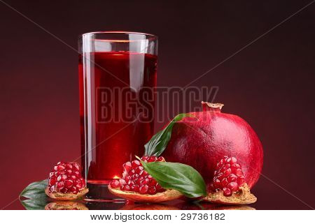 rijpe pomergranate en glas sap op rode achtergrond