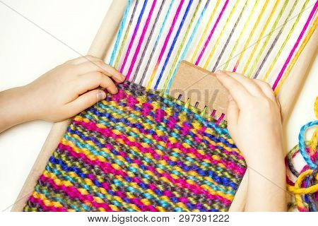 Weaving. Hands Of Little Caucasian Girl Working On Small Loom Weaving.
