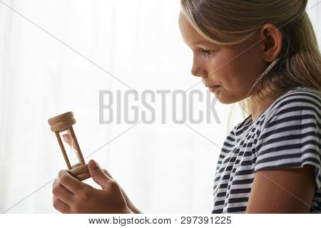 Pretty Curious Little Girl Looking At Hourglass In Her Hand