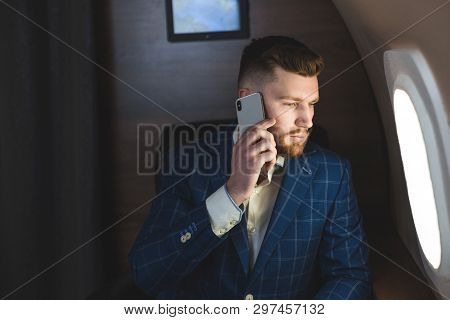 Young Attractive And Successful Businessman Talking On The Phone And Working While Sitting In The Ch