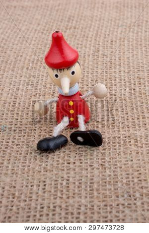 Wooden Pinocchio Doll Sitting On Canvas Background