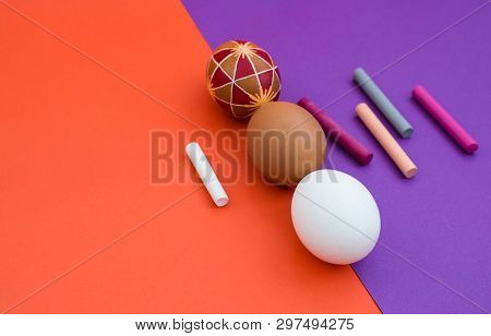 Three Eggs And Colorful Crayon Lie On Dichromatic Background.