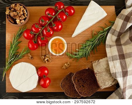 Rye Bread With Brie And Camembert Cheeses, Nuts, Honey, Cherry Tomatoes And Rosemary On A Wooden Boa