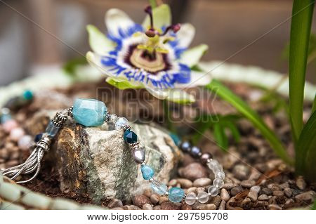 Jewelery Made Of Natural Stones Against The Backdrop Of Blossoming Pasiflora. Bracelets, Rings, Neck