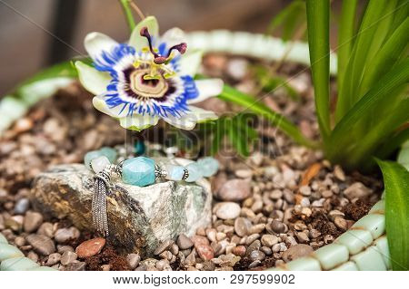 Jewelery Made Of Natural Stones Against The Backdrop Of Blossoming Pasiflora. Bracelets, Rings, Neck