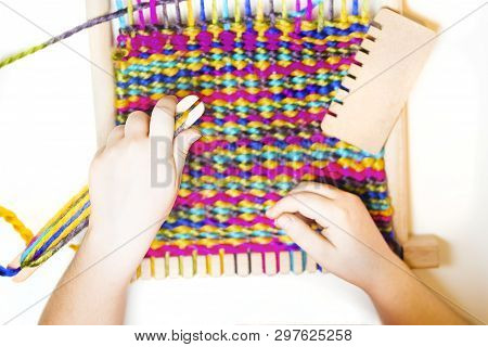 Weaving. Hands Of Little Caucasian Girl Working On Small Loom Weaving.