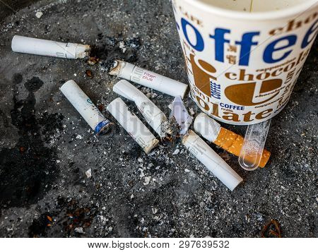 Miercurea Ciuc, Romania- 25 April 2019: Cigarette Butts And Coffee Paper Cup On Dirty Ashtray.