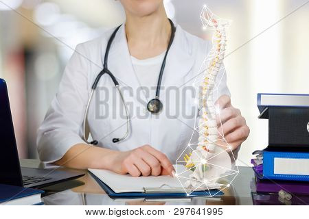 A Closeup Of Doctor At Table With Notebook And Patient Medical Card On It Holding A Spin Skeleton Wi