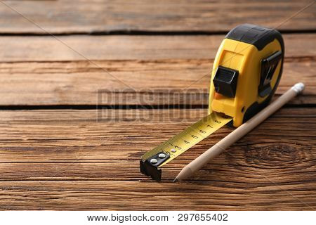 Metal Measuring Tape And Pencil On Wooden Background. Space For Text