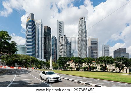 Taxi Cab Driving In Road In Singapore Downtown With Singapore Skyscrapers Building In Background. As