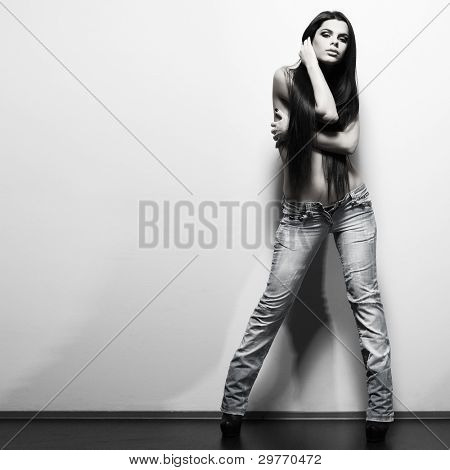Fotografie sexuální krasavicí v džínách, stojící nedaleko walll je v módní styl, kouzlo