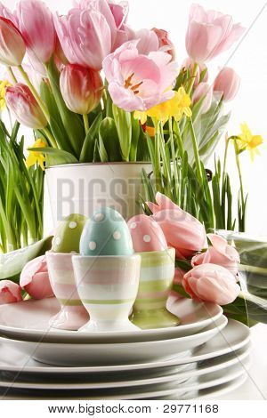 Ostereier in Tassen mit Frühlingsblumen auf weißem Hintergrund