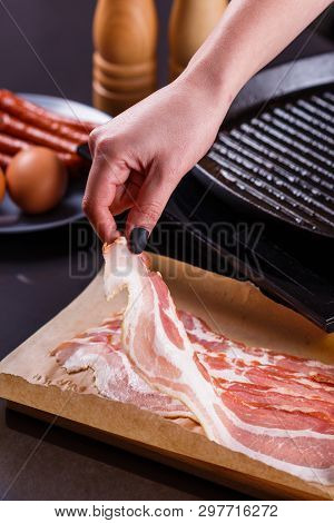 Young Woman In A Gray Apron Fries Bacon