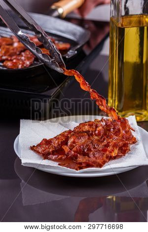 Young Woman In A Gray Apron Fries Bacon