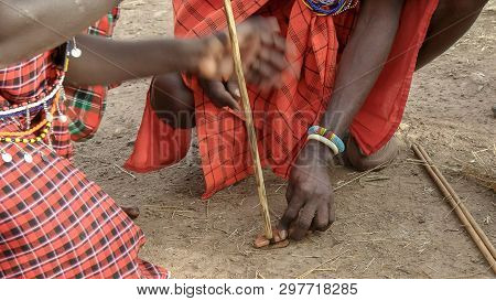 Two Maasai Men Use A Traditional Hand Drill To Start A Fire Without Matches At A Manyatta In Kenya