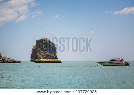 The Rock In The Andaman Sea Is Painted With Gold Paint. Thai Spirituality. Speedboat Floats Nearby. 