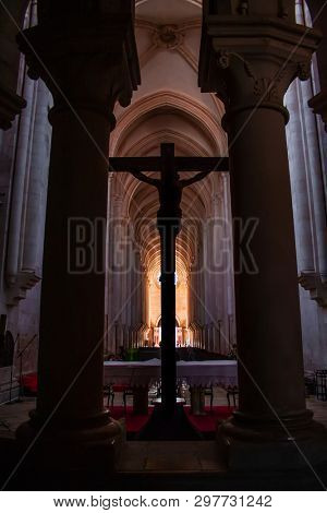 Alcobaca, Portugal - July 17, 2017: Crucifix with Jesus Christ nailed to cross in altar of Monastery of Santa Maria de Alcobaca Abbey. Medieval Gothic architecture. Cistercian Religious Order