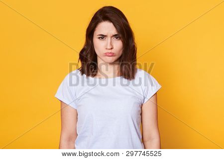 Portrait Of Beautiful Dark Haired Young Woman In Casual White T Shirt, Standing And Looking Directly