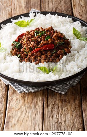Thai Basil Chicken With Spicy Chili Pepper And Soy Sauce With Rice Garnish Close-up On A Plate. Vert