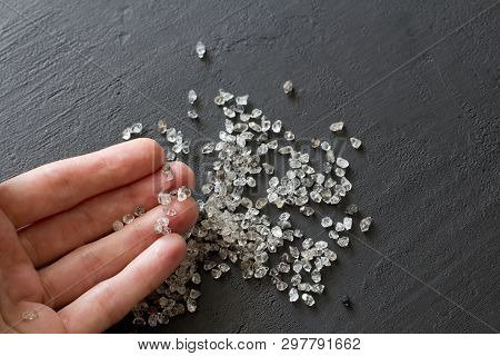 Raw Natural Diamonds, Graphite Quartz Are In The Hand. A Scattering Of Small Stones Lies In The Fema