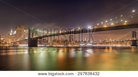 A Panorama Of The Brooklyn Bridge At Night With The New York City Skyline In The Background. The Eas