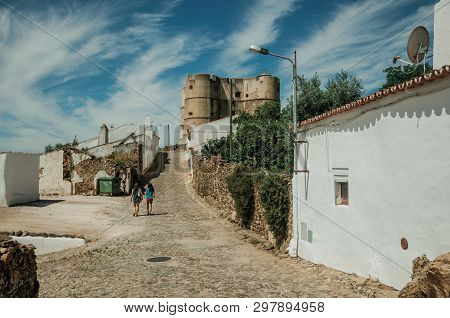Evoramonte, Portugal - July 6, 2018. People Walking Up The Cobblestone Street Towards The Castle Of 