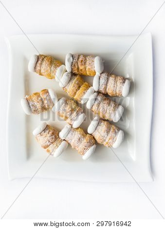 Ten small delicious cream rolls on a rectangular plate