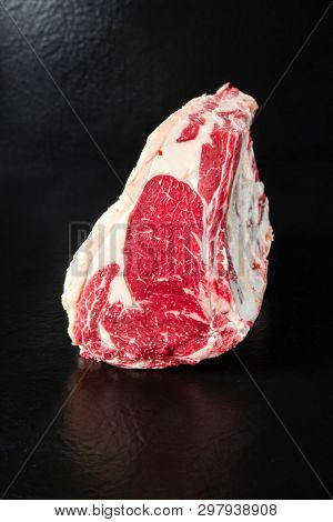 Raw dry aged wagyu cote de boeuf beef block as closeup on black background with copy space
