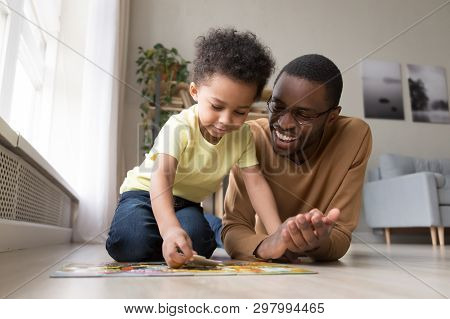 African Father And Little Son Collect Jigsaw Puzzle At Home