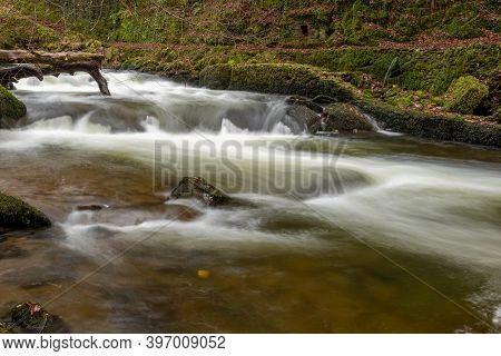 Long Exposure Of A Waterfall On The East Lyn River Flowing Through The Woods At Watersmeet In Exmoor