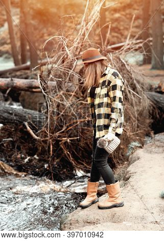 Woman In Yellow Shirt And Hat Walking Along The River In The Autumn Forest