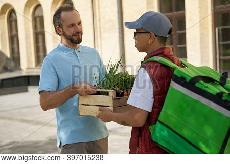 Young Male Courier With Thermo Bag Giving Wooden Box With Fresh