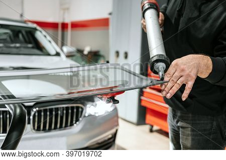 Glazier Applying Rubber Sealing To Windshield In Garage, Close Up. High Quality Photo