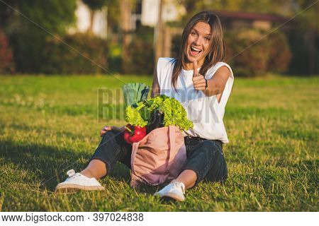 Beautiful Happy Smiling Vegan Woman Sitting On The Grass With Pink Eco Reusable Grocery Bag With Fre